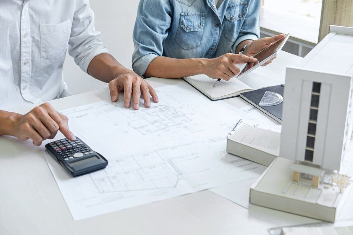 Calcolatrice, planimetria e modello architettonico su un tavolo di lavoro